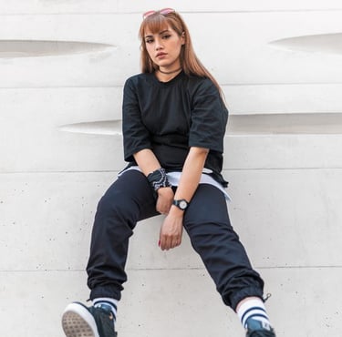woman in black long sleeve shirt and blue denim jeans sitting on white concrete wall