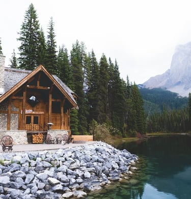 brown wooden house near lake surrounded by green trees during daytime
