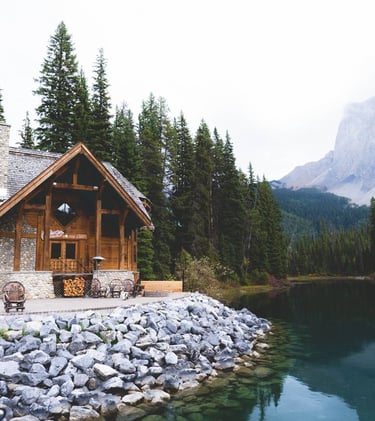 brown wooden house near lake surrounded by green trees during daytime