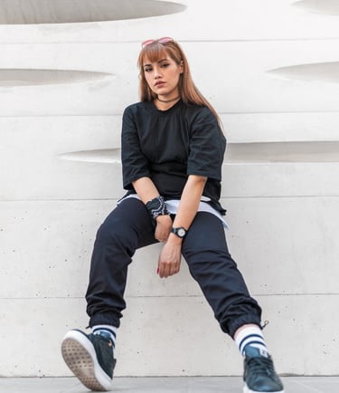woman in black long sleeve shirt and blue denim jeans sitting on white concrete wall