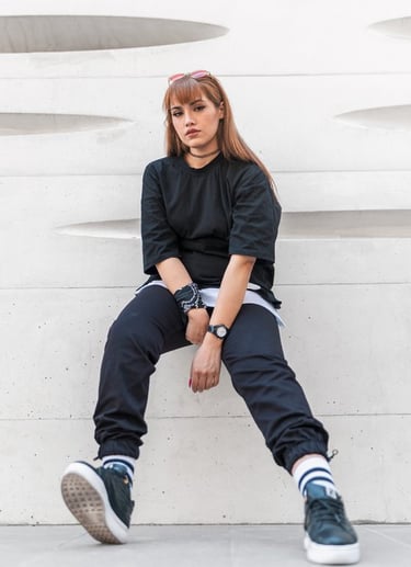 woman in black long sleeve shirt and blue denim jeans sitting on white concrete wall