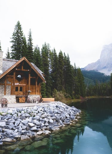 brown wooden house near lake surrounded by green trees during daytime