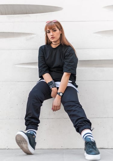 woman in black long sleeve shirt and blue denim jeans sitting on white concrete wall