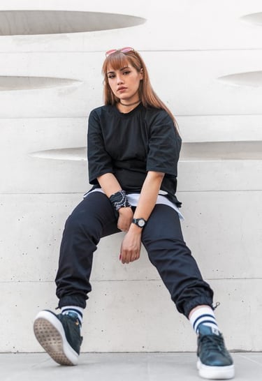woman in black long sleeve shirt and blue denim jeans sitting on white concrete wall