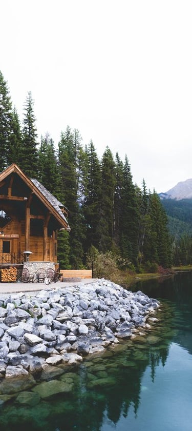 brown wooden house near lake surrounded by green trees during daytime