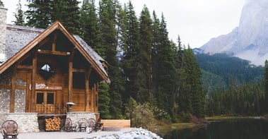 brown wooden house near lake surrounded by green trees during daytime