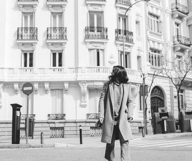 man in black coat walking on sidewalk in grayscale photography