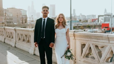 man in black suit standing beside woman in white wedding dress