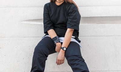 woman in black long sleeve shirt and blue denim jeans sitting on white concrete wall
