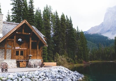 brown wooden house near lake surrounded by green trees during daytime