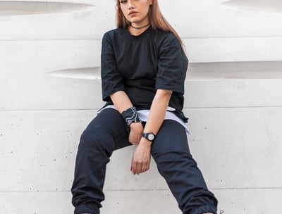 woman in black long sleeve shirt and blue denim jeans sitting on white concrete wall