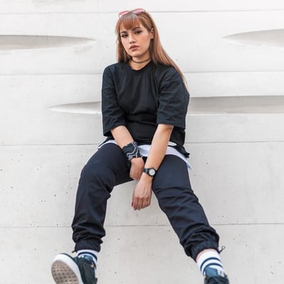 woman in black long sleeve shirt and blue denim jeans sitting on white concrete wall