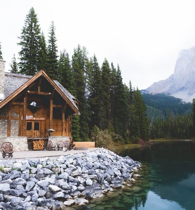 brown wooden house near lake surrounded by green trees during daytime