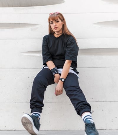 woman in black long sleeve shirt and blue denim jeans sitting on white concrete wall