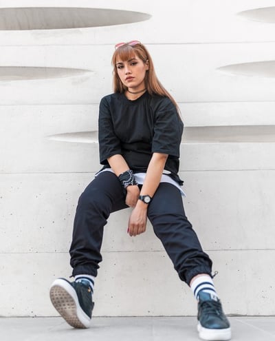 woman in black long sleeve shirt and blue denim jeans sitting on white concrete wall