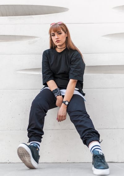 woman in black long sleeve shirt and blue denim jeans sitting on white concrete wall
