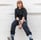 woman in black long sleeve shirt and blue denim jeans sitting on white concrete wall