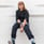 woman in black long sleeve shirt and blue denim jeans sitting on white concrete wall