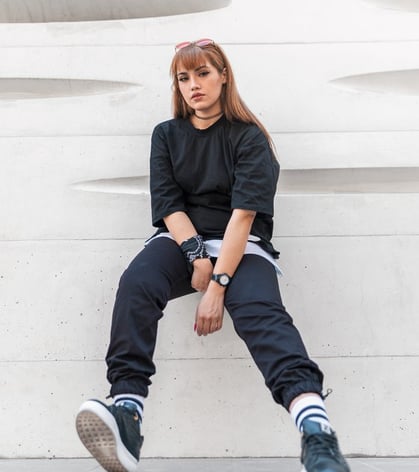 woman in black long sleeve shirt and blue denim jeans sitting on white concrete wall