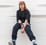 woman in black long sleeve shirt and blue denim jeans sitting on white concrete wall