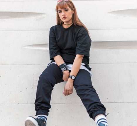 woman in black long sleeve shirt and blue denim jeans sitting on white concrete wall