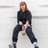 woman in black long sleeve shirt and blue denim jeans sitting on white concrete wall