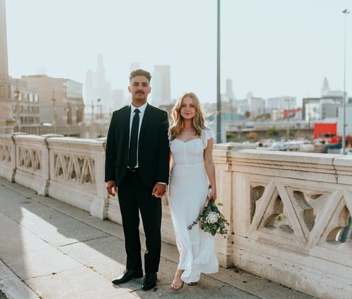 man in black suit standing beside woman in white wedding dress
