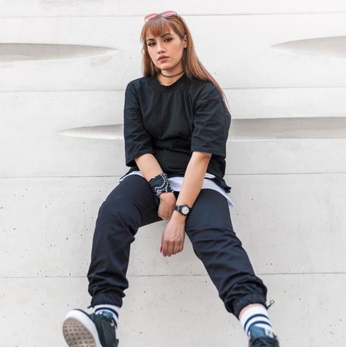 woman in black long sleeve shirt and blue denim jeans sitting on white concrete wall