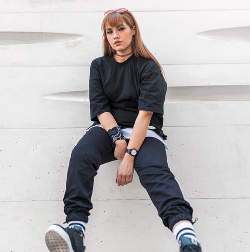 woman in black long sleeve shirt and blue denim jeans sitting on white concrete wall