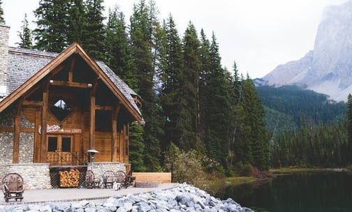brown wooden house near lake surrounded by green trees during daytime