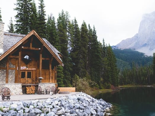 brown wooden house near lake surrounded by green trees during daytime