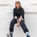 woman in black long sleeve shirt and blue denim jeans sitting on white concrete wall