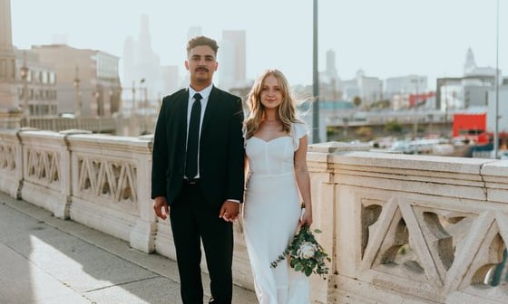 man in black suit standing beside woman in white wedding dress