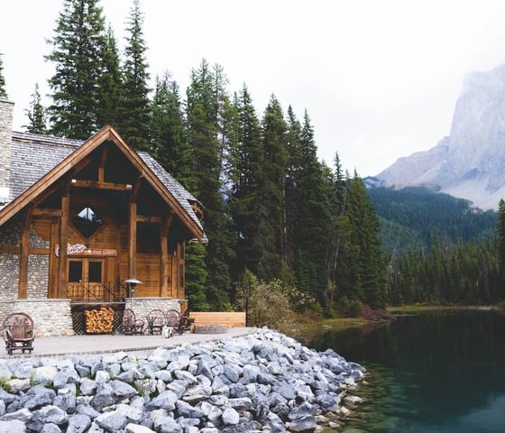 brown wooden house near lake surrounded by green trees during daytime