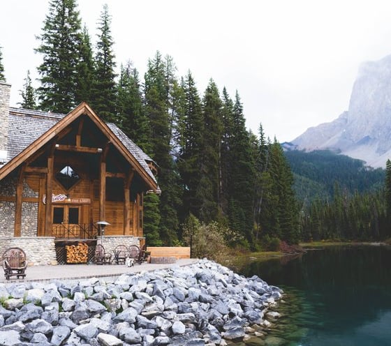 brown wooden house near lake surrounded by green trees during daytime
