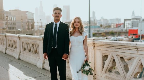 man in black suit standing beside woman in white wedding dress