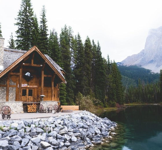 brown wooden house near lake surrounded by green trees during daytime