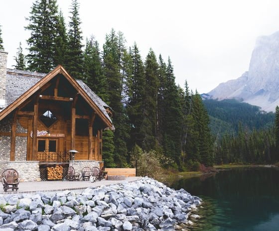 brown wooden house near lake surrounded by green trees during daytime