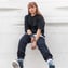 woman in black long sleeve shirt and blue denim jeans sitting on white concrete wall