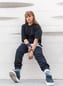 woman in black long sleeve shirt and blue denim jeans sitting on white concrete wall