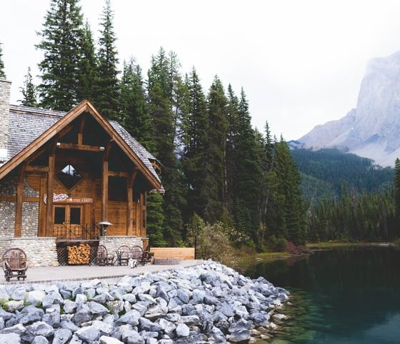 brown wooden house near lake surrounded by green trees during daytime