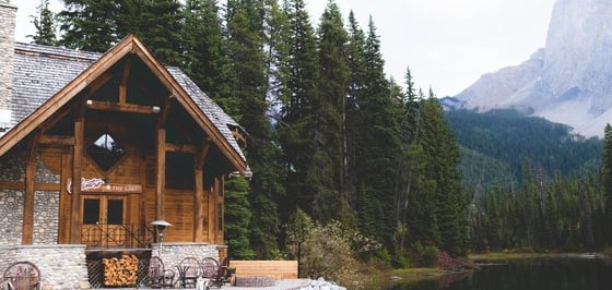brown wooden house near lake surrounded by green trees during daytime