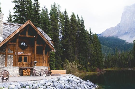 brown wooden house near lake surrounded by green trees during daytime