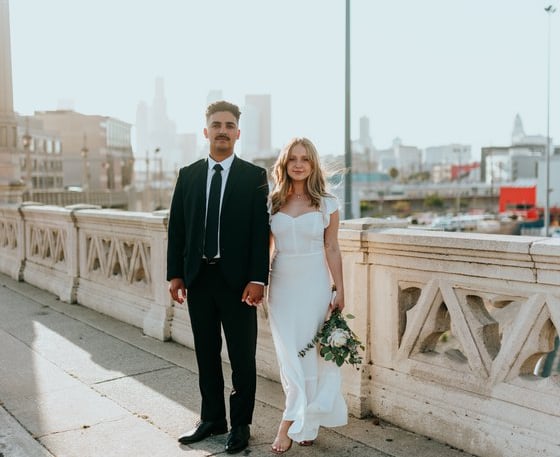 man in black suit standing beside woman in white wedding dress