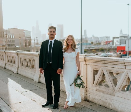 man in black suit standing beside woman in white wedding dress
