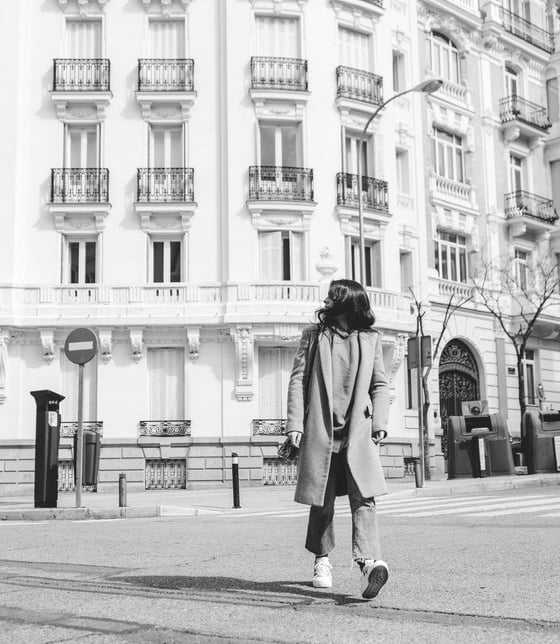 man in black coat walking on sidewalk in grayscale photography