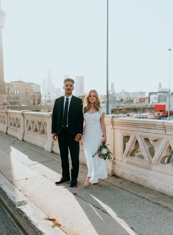 man in black suit standing beside woman in white wedding dress