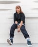 woman in black long sleeve shirt and blue denim jeans sitting on white concrete wall