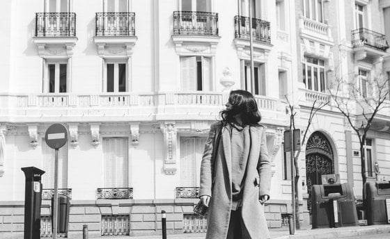 man in black coat walking on sidewalk in grayscale photography