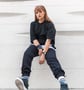 woman in black long sleeve shirt and blue denim jeans sitting on white concrete wall
